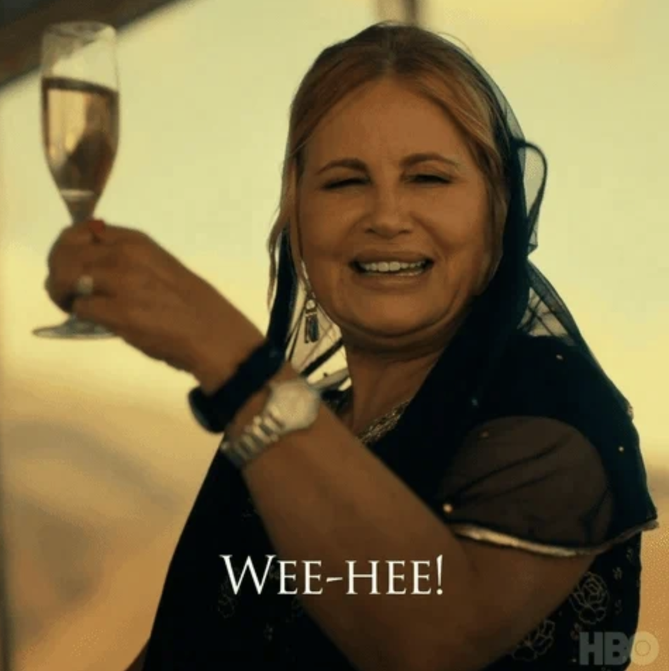 Jennifer Coolidge in a black veil holding up a champagne and saying &quot;wee-hee&quot;