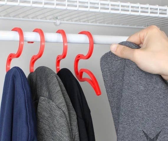 four hoodie hangers mounted on a closet rod with sweatshirts hanging from them