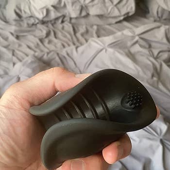 Reviewer holding black vibrating stroker to show interior
