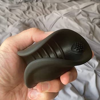 Reviewer holding black vibrating stroker to show interior