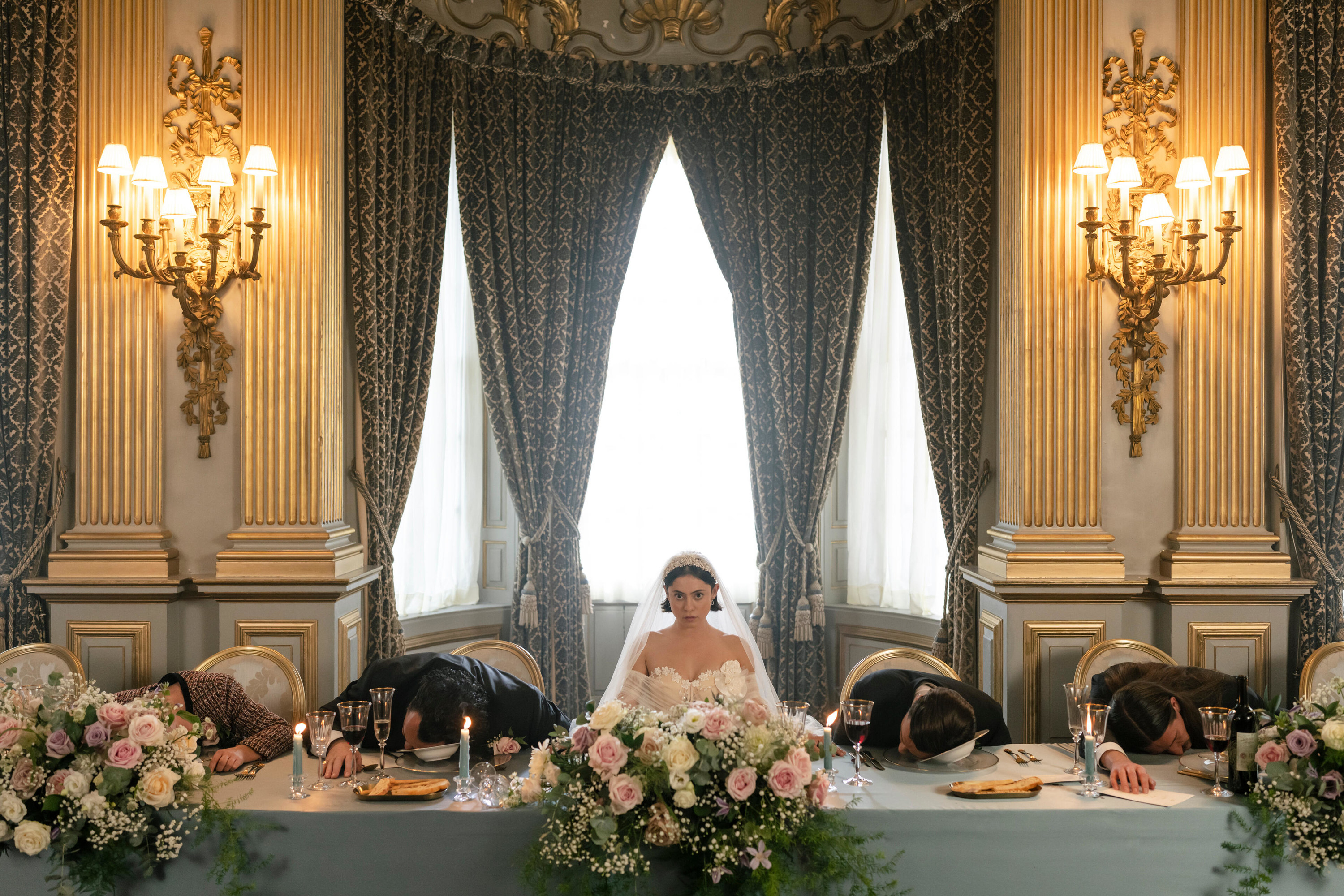 a bride sitting at a table as all the other people at the table are slumped forward