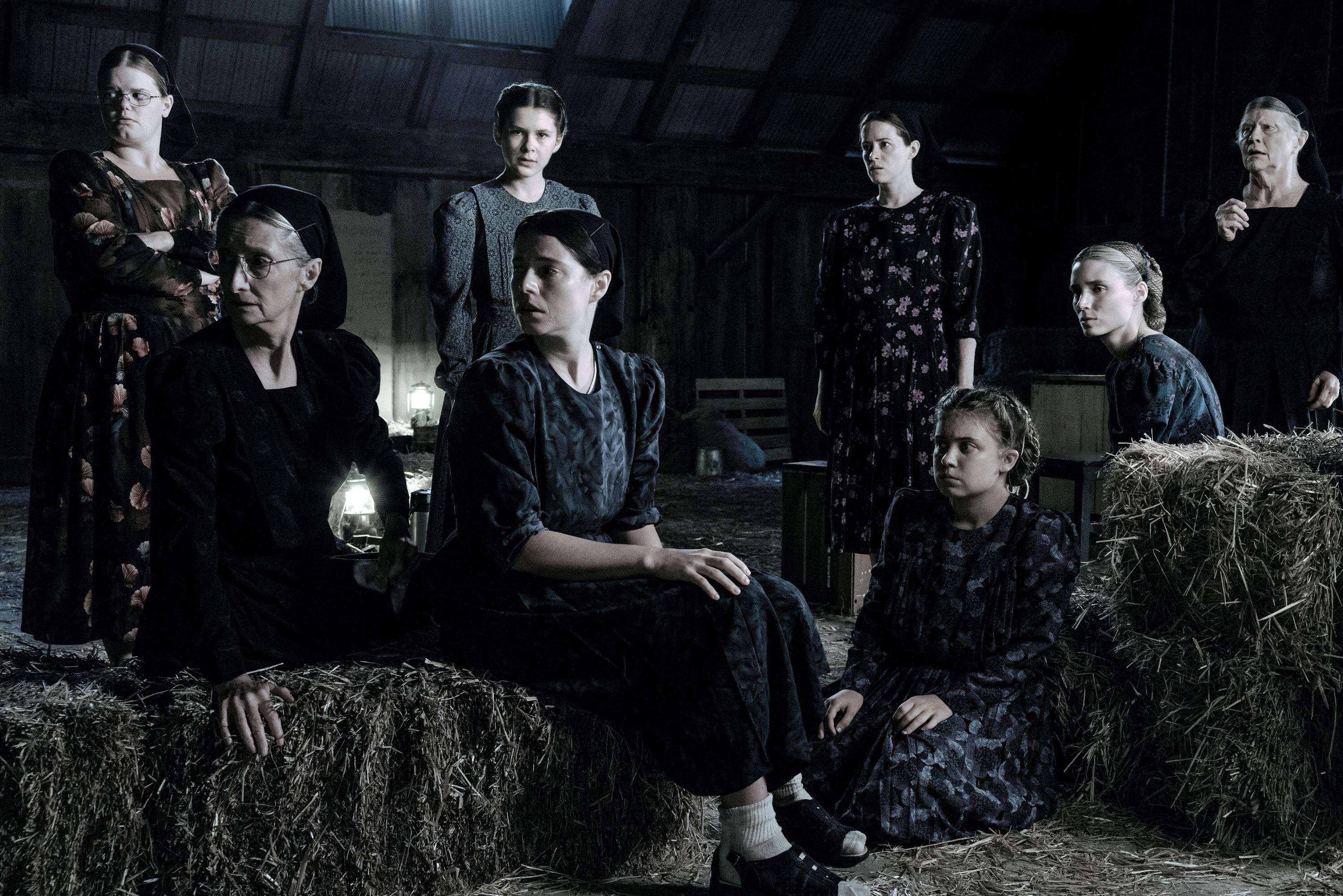 A group of women sit together in a barn
