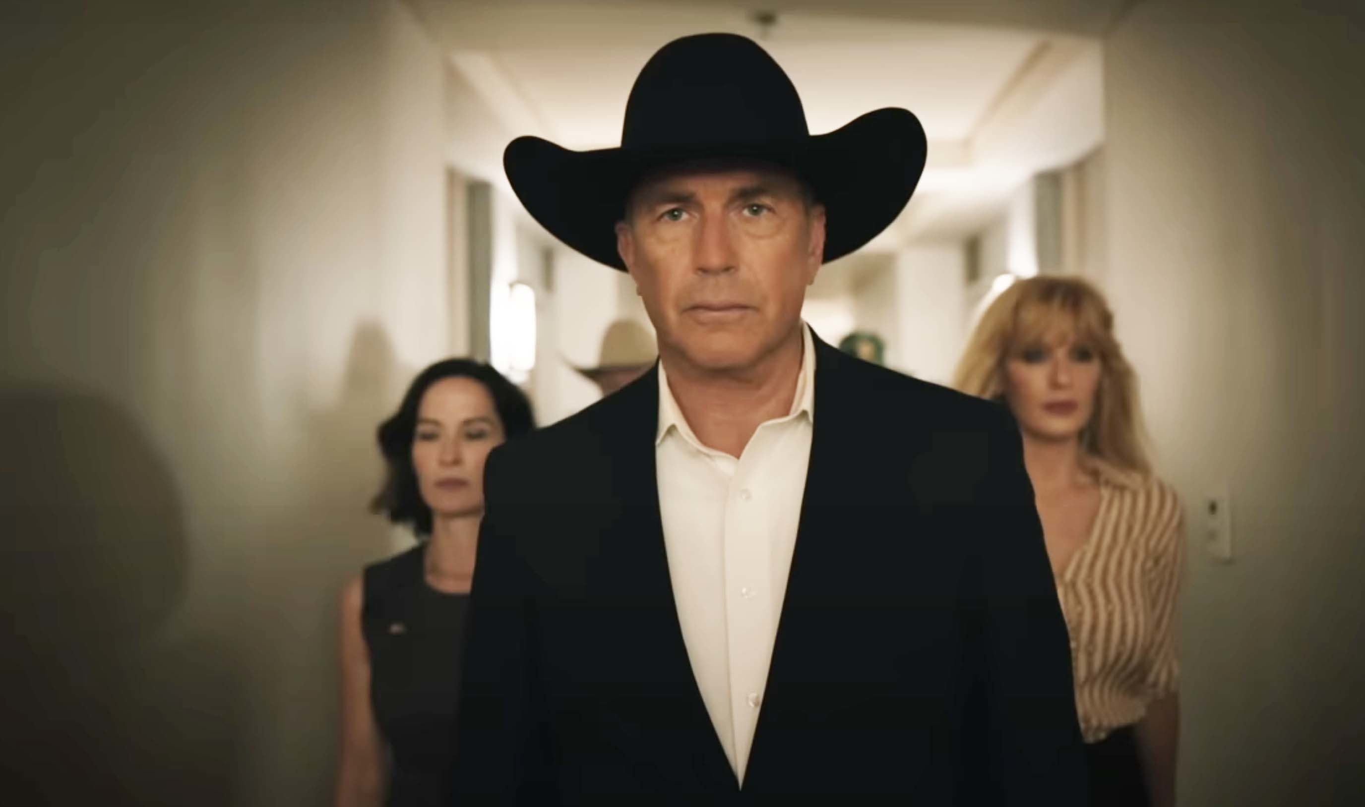 a man in a cowboy hat leading people down a hallway