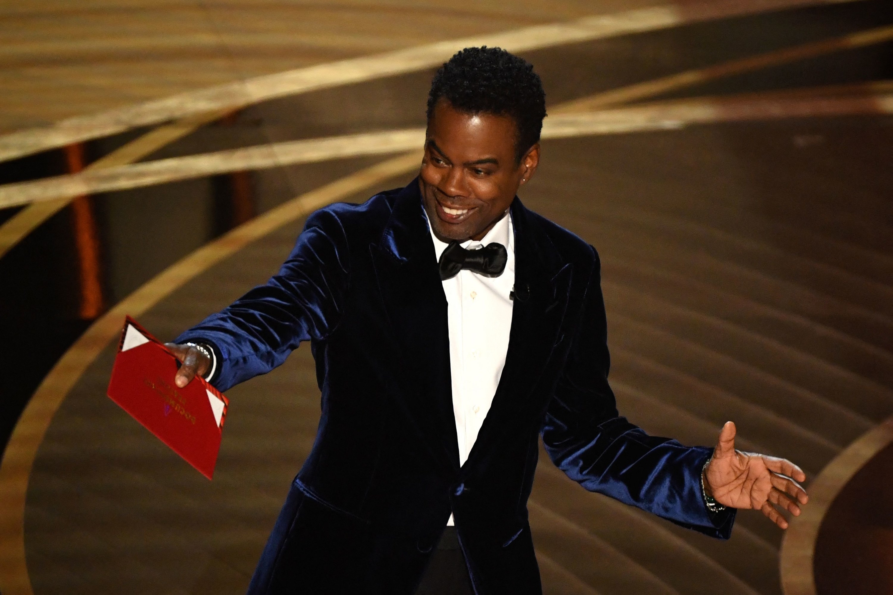 Chris Rock onstage holding an envelope