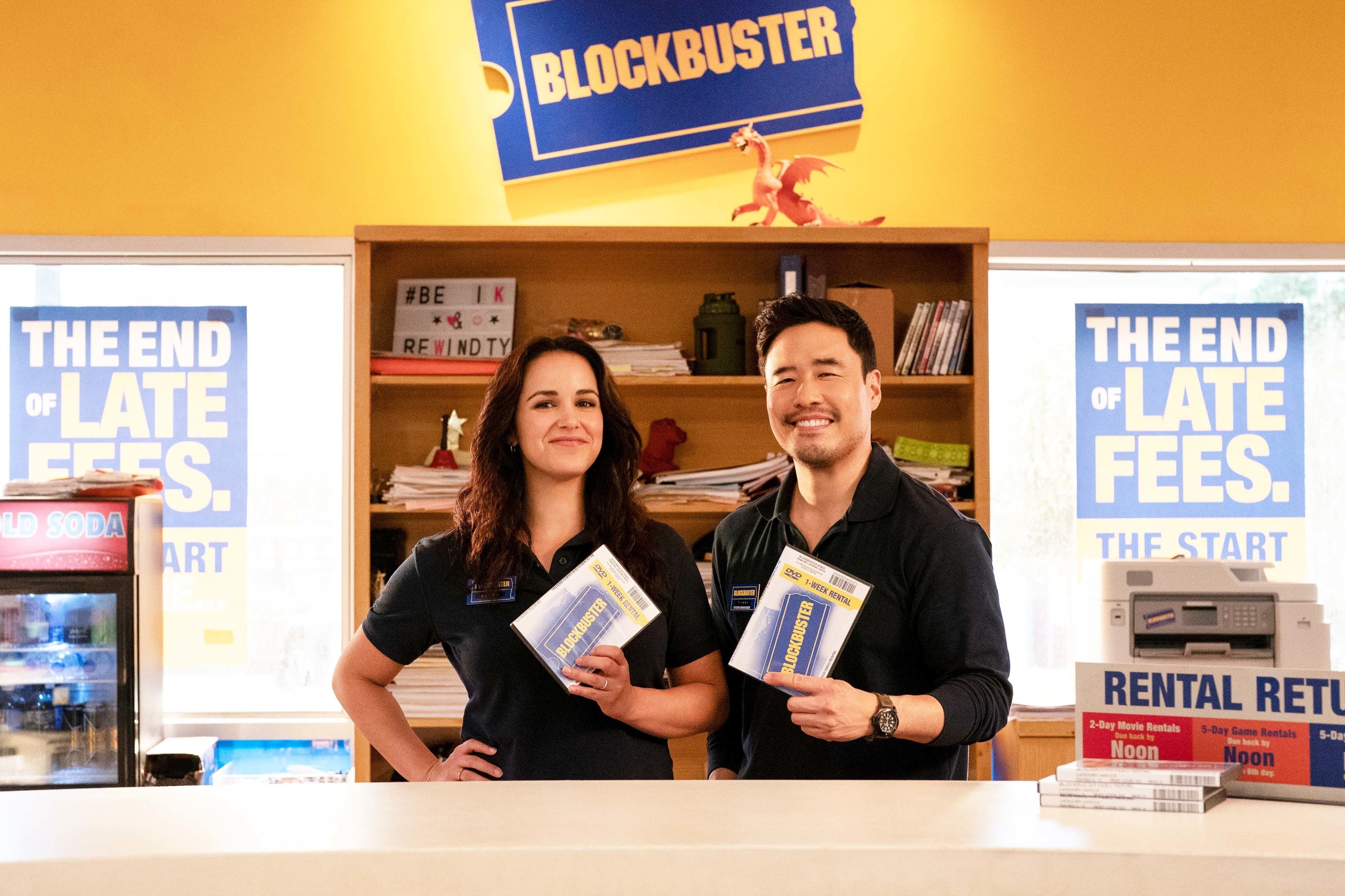 a man and a woman holding up rentals at a Blockbuster
