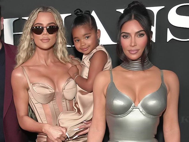 A closeup of Khloé holding True while standing next to Kim at an event