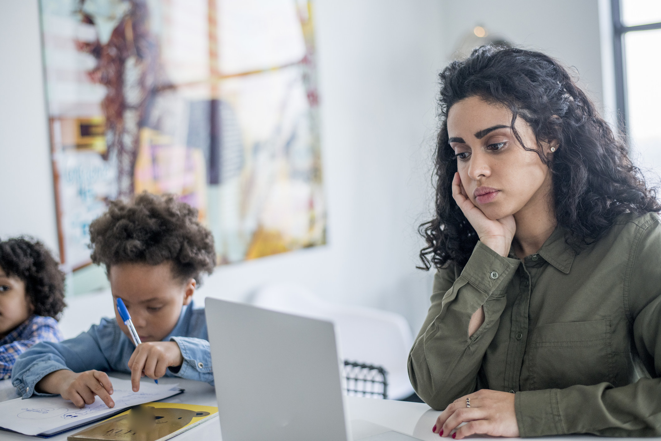 Young woman sitting at a laptop with two children next to her