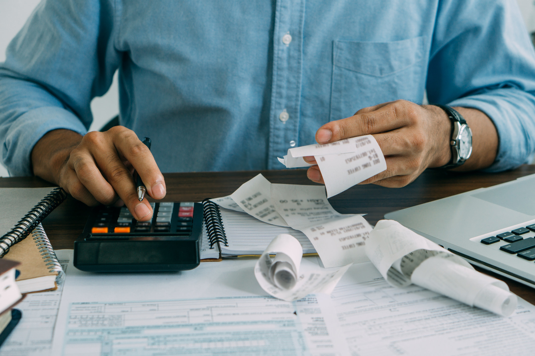 Person working at a calculator and holding receipts