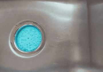 blue foaming cleanser pushing its way out of the sink drain