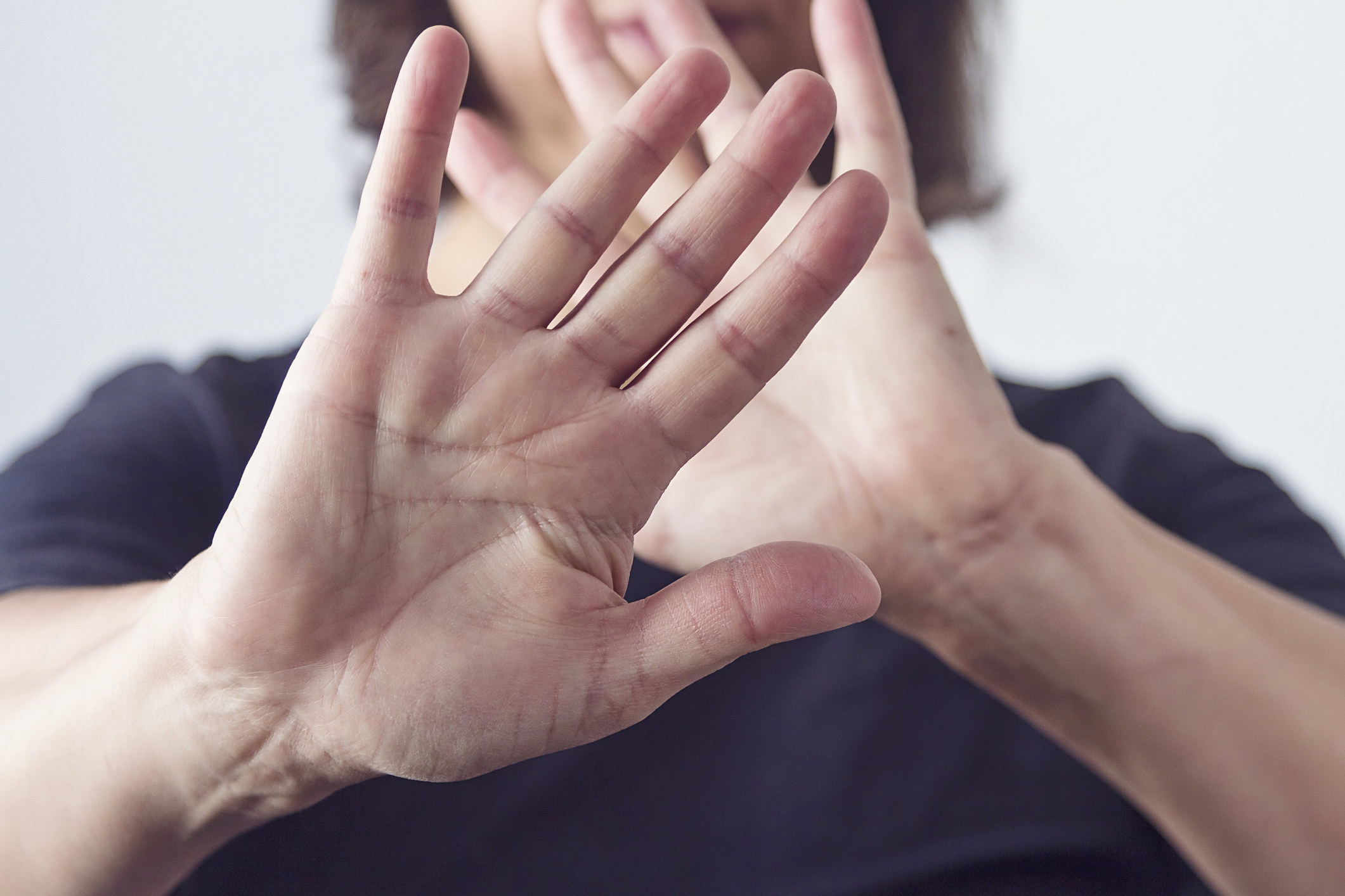 Person with hands held up to cover their face