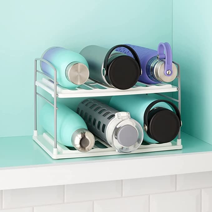 the water bottle organizer in a cupboard with bottles stored on it