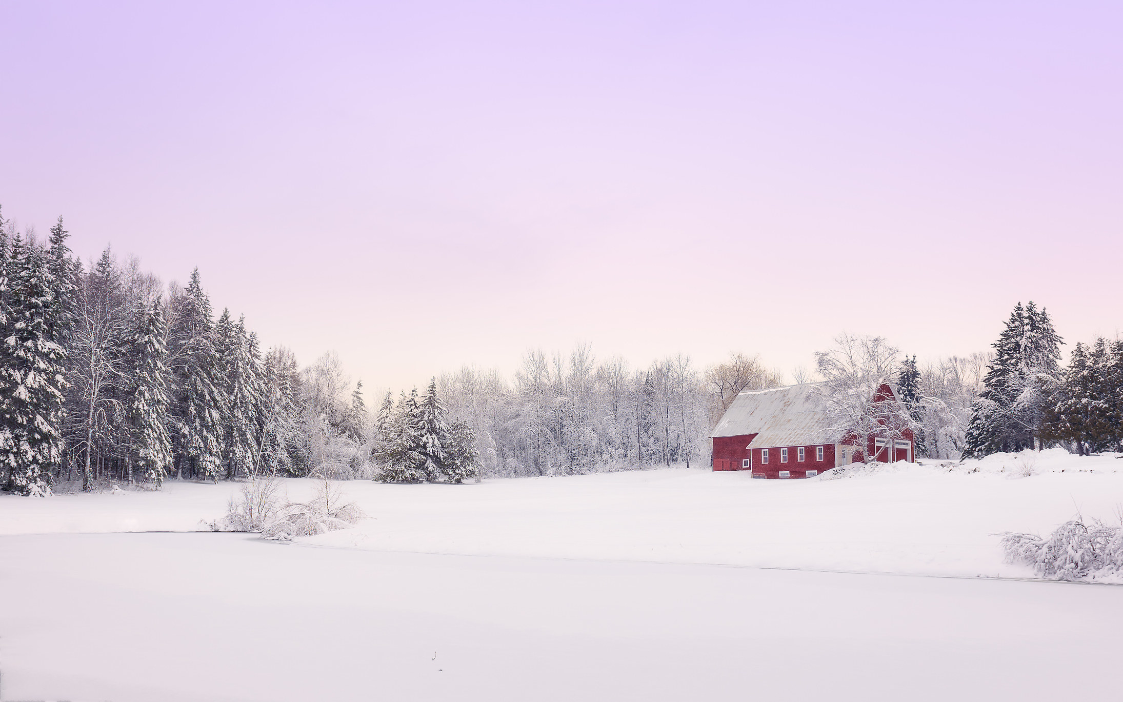 a red barn surrounded by snow