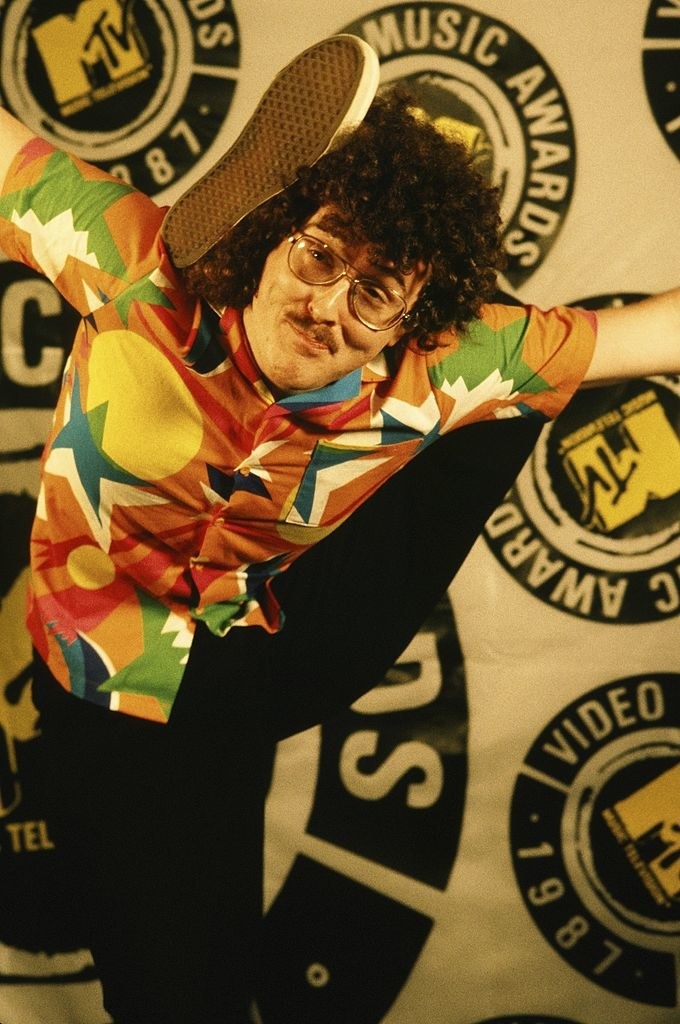 weird al in a colorful shirt, glasses and curly hair