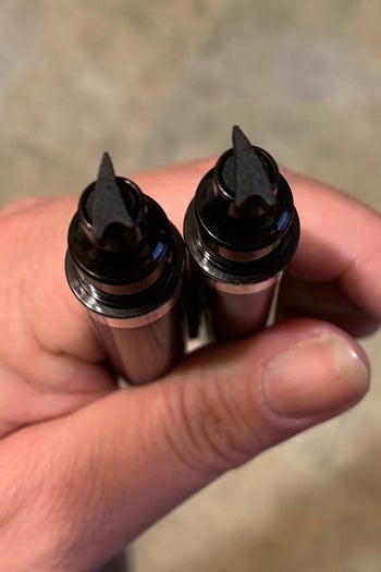 a hand holding the two eyeliner stamps for each eye