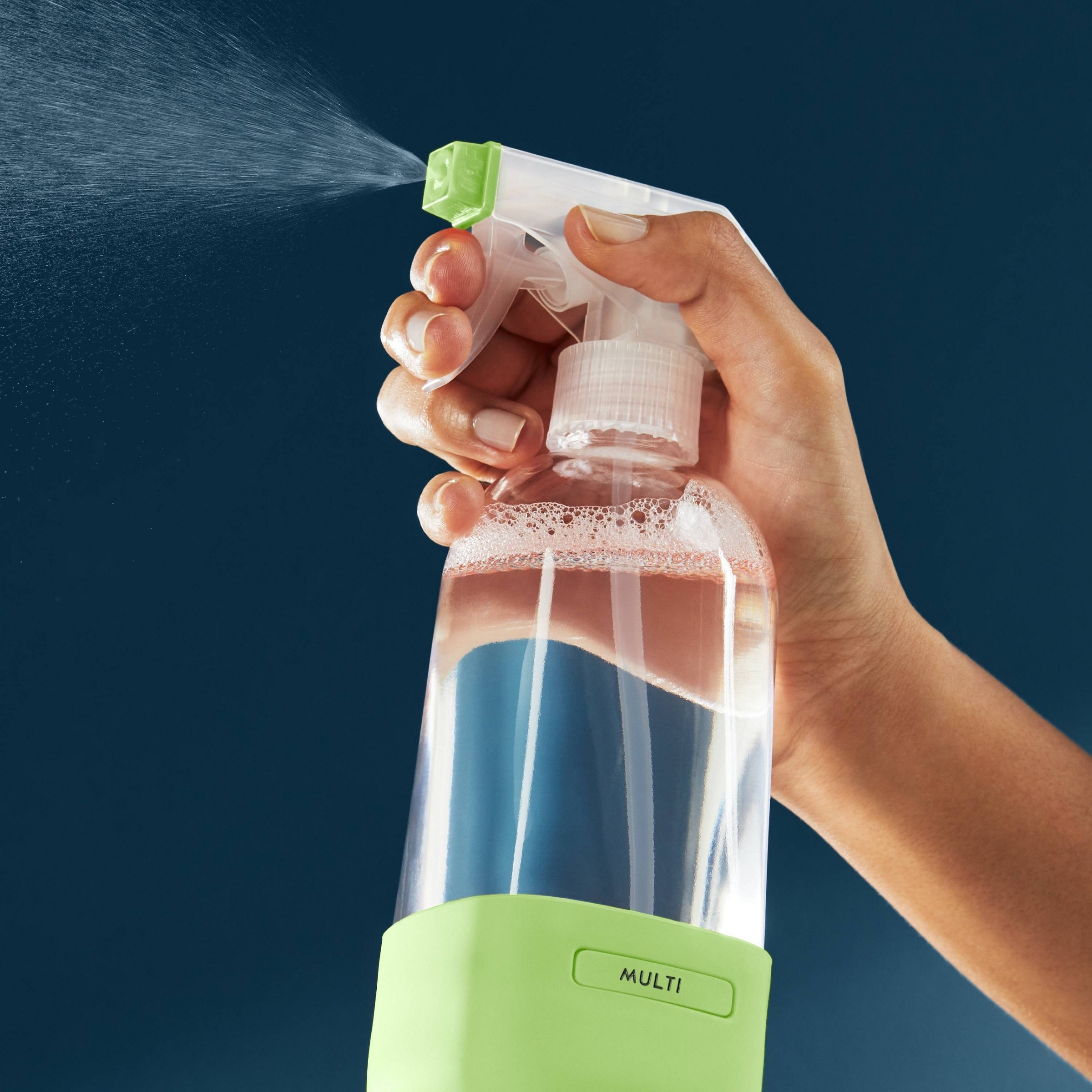 a hand holding the glass spray bottle with lime green base