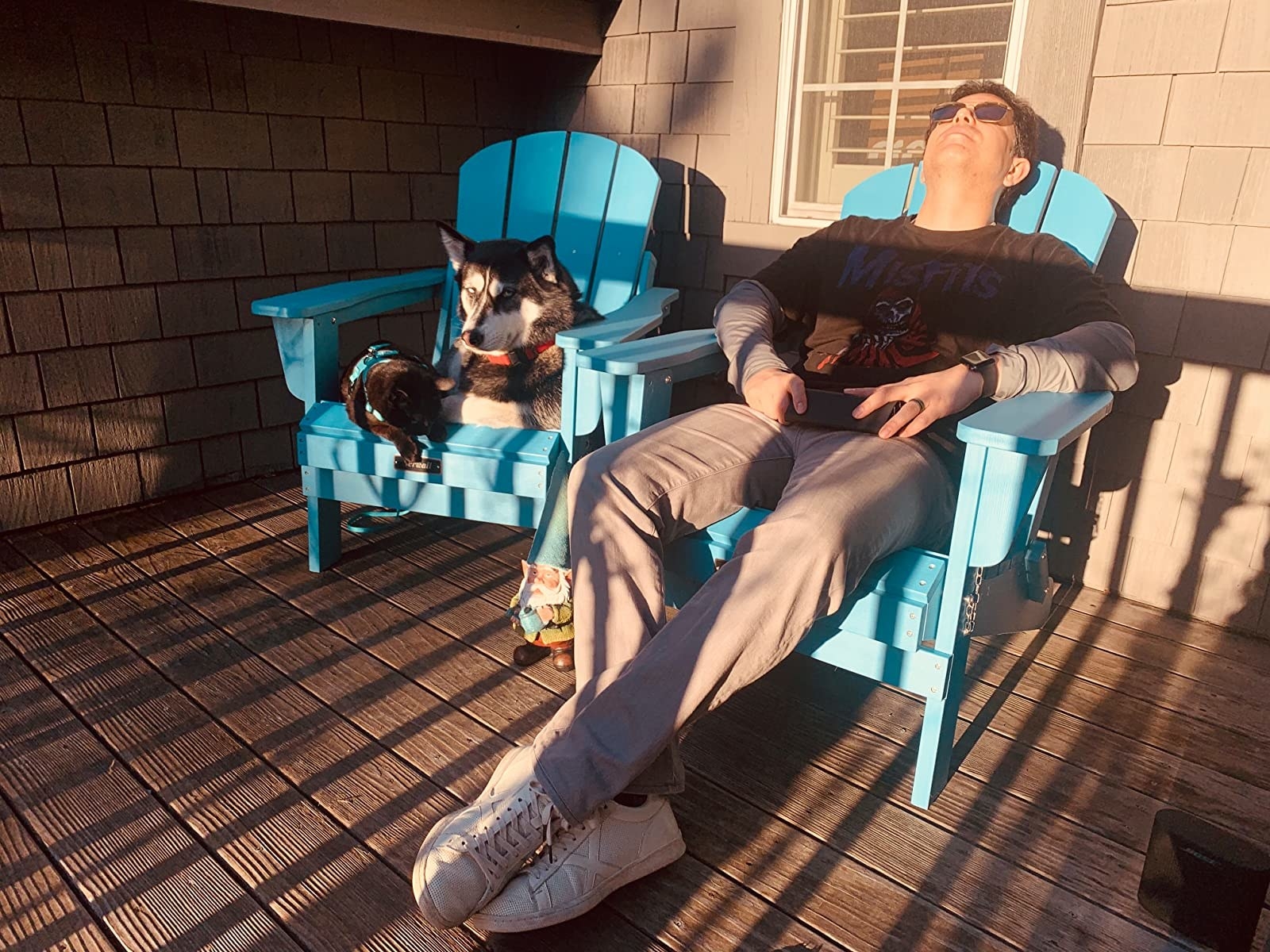 Reviewer and their dog sit comfortably in a pair of teal outdoor chairs