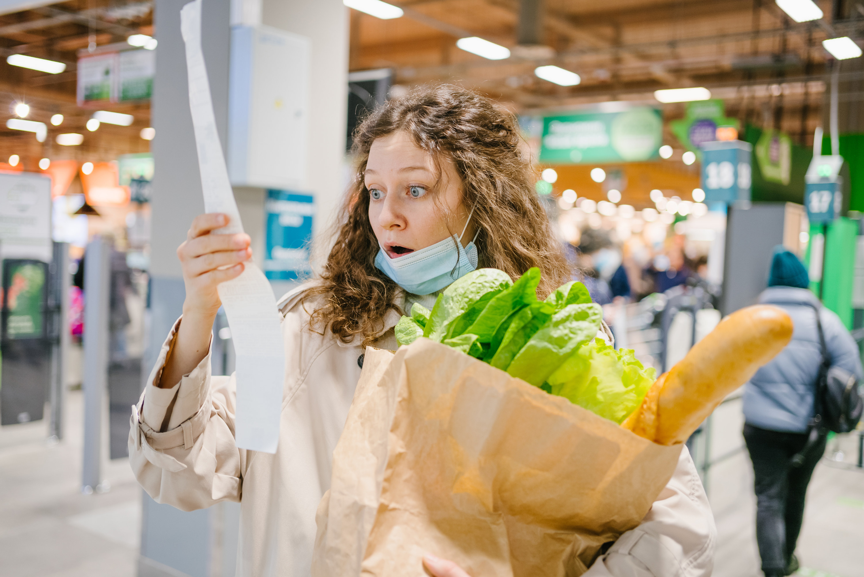 woman looking shocked at her grocery receipt