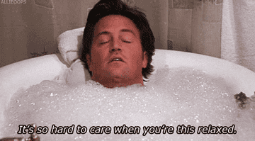 Chandler from Friends in a bathtub filled with bubbles with the caption &quot;It&#x27;s so hard to care when you&#x27;re this relaxed&quot;