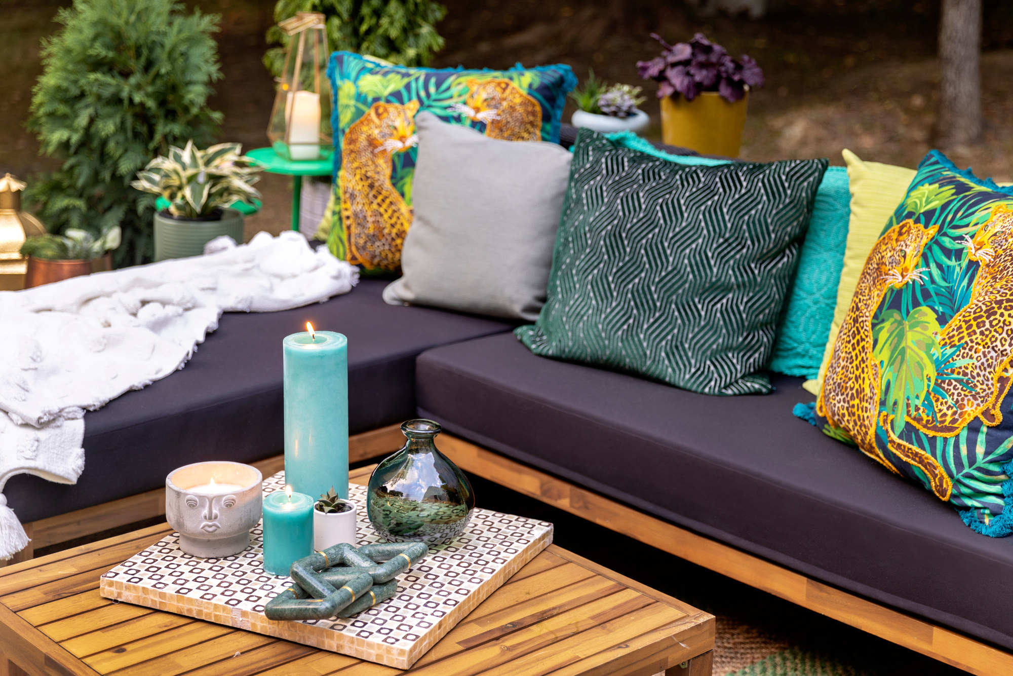 Outdoor seating with pillows placed near tables with candles and vases