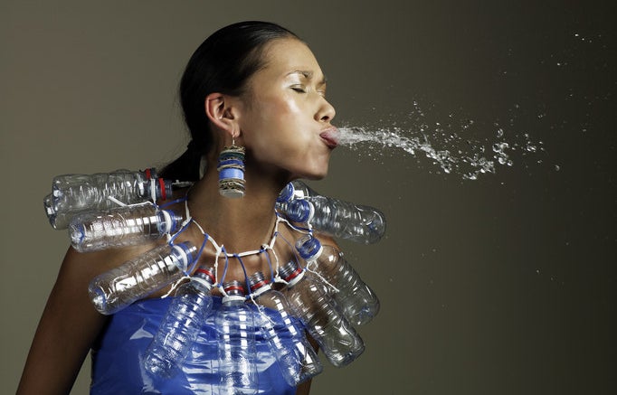 A woman spitting water with a water-bottle necklace