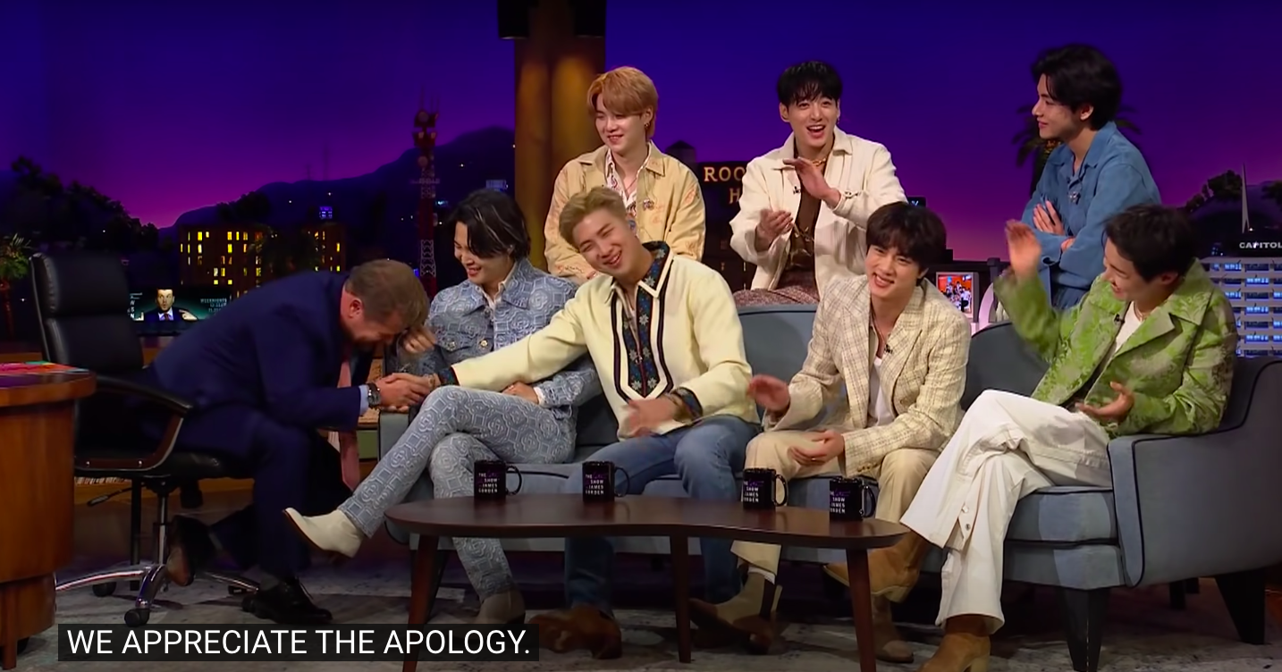 James shaking the hand of a BTS member and bowing with caption &quot;We appreciate the apology&quot;