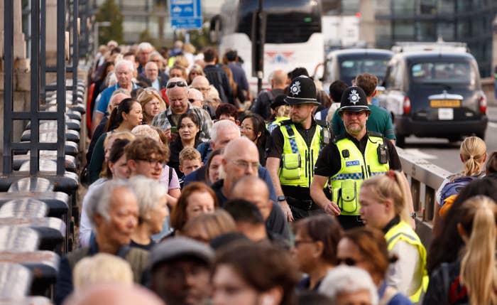 Scores of people are seen in line as two police officers watch on