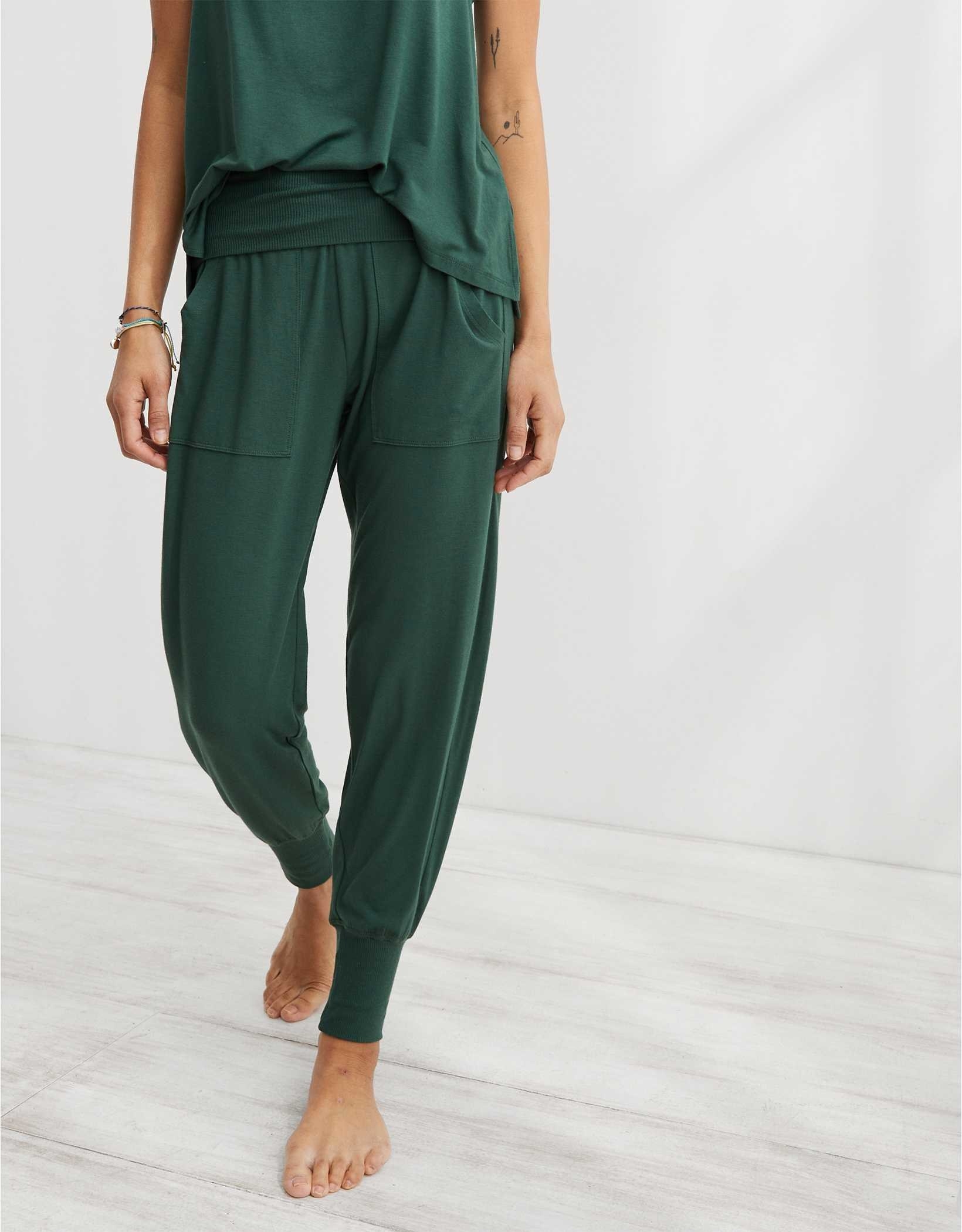 model in dark green drapey joggers with a folded waistband and thick ankle bands