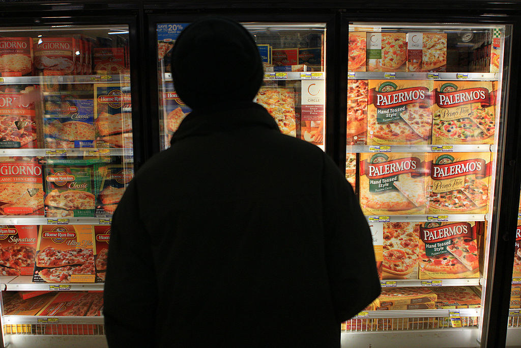 Man looking at frozen pizzas in the grocery store