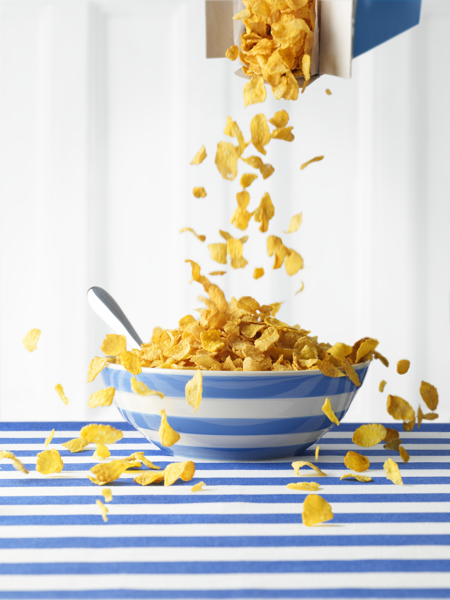 Flake cereal being poured into an overflowing bowl