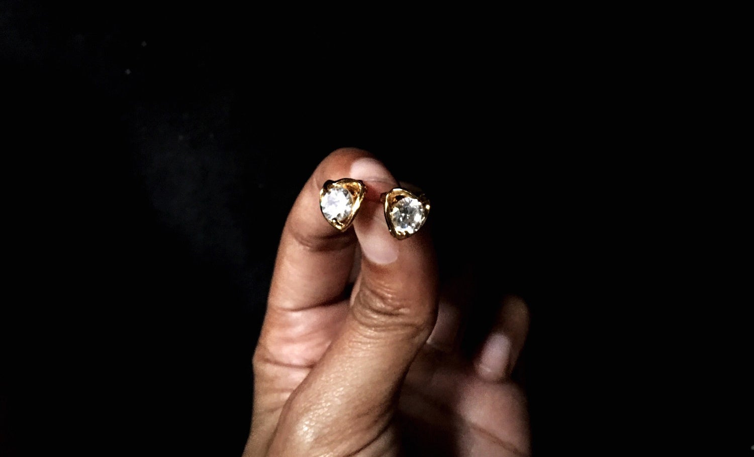 a person&#x27;s hand holding diamond earrings