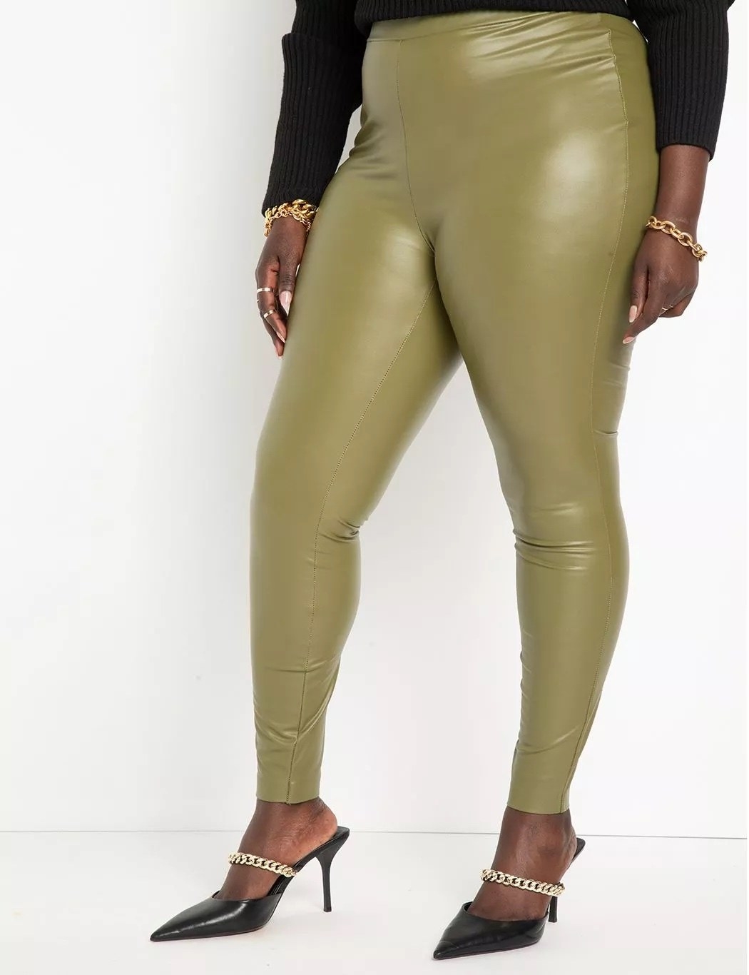 A model wearing green leggings with black shoes and a black top