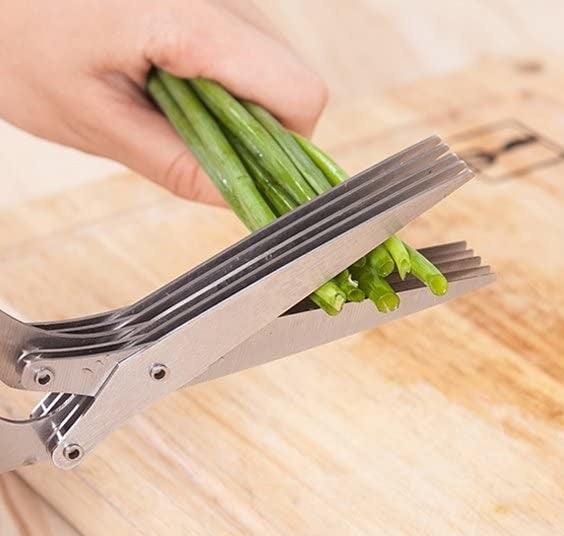 person snipping a green onion with the scissors