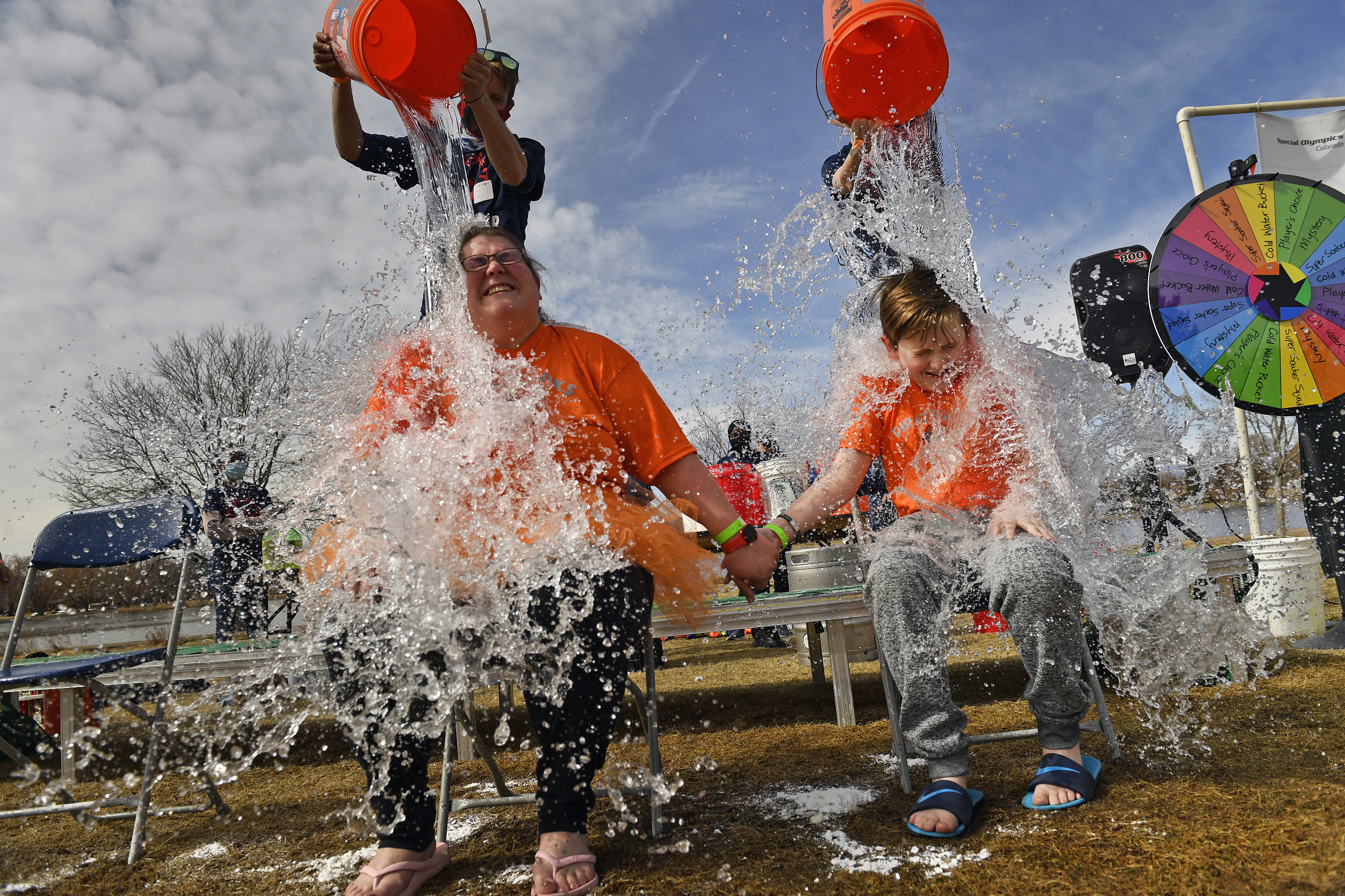 Sarah Ellis, left, and her son Topher, 10, get doused with buckets of cold water as they take part in the Denver Polar Plunge to support Special Olympics on March 7, 2021