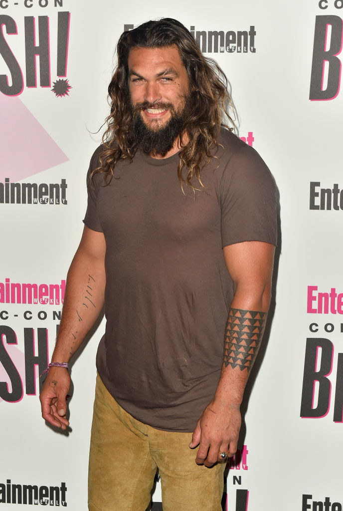 A red carpet photo featuring Jason&#x27;s arm tattoo, which features columns of arrows encircling his forearm and pointing down toward his hand