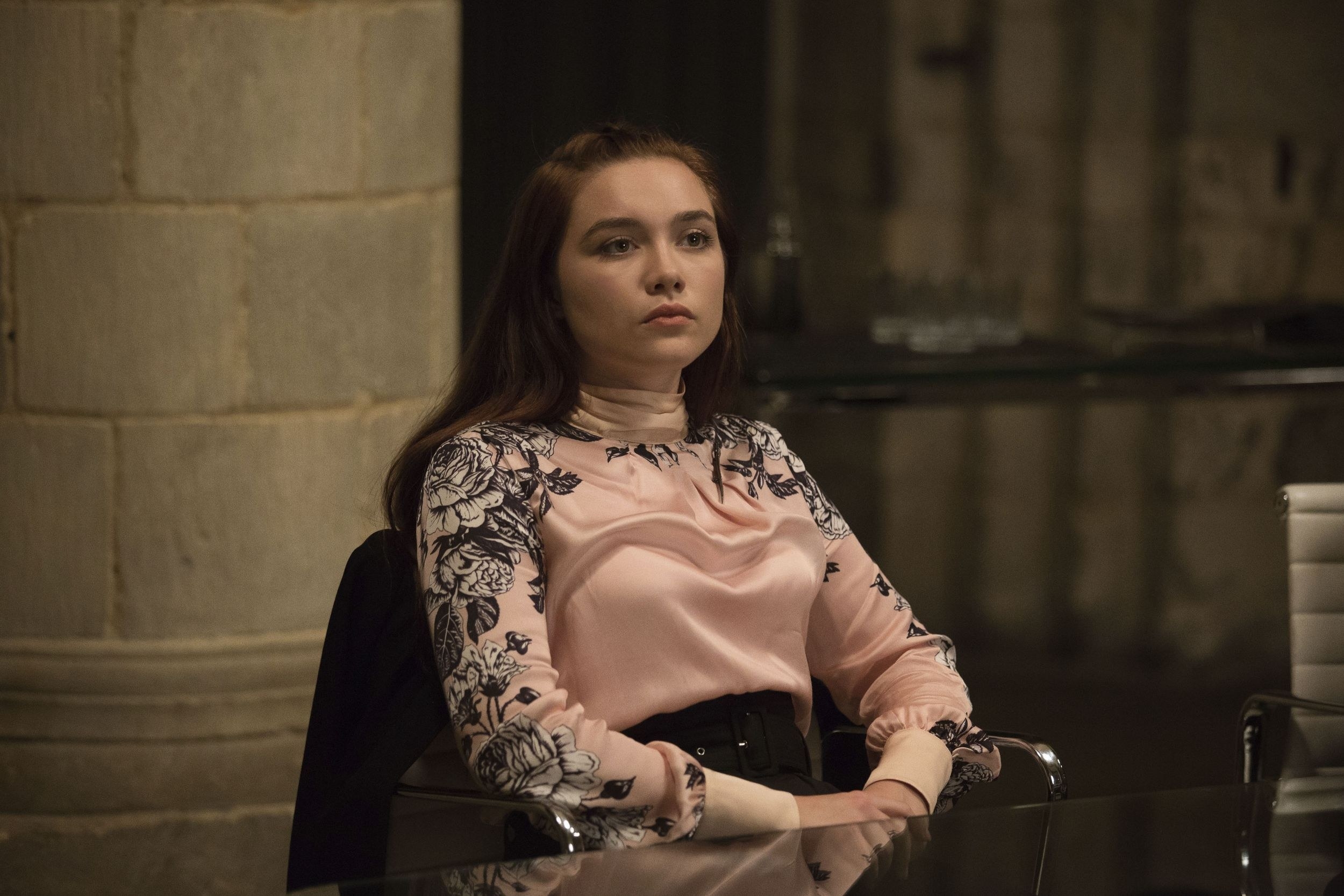 Florence Pugh sits at a table