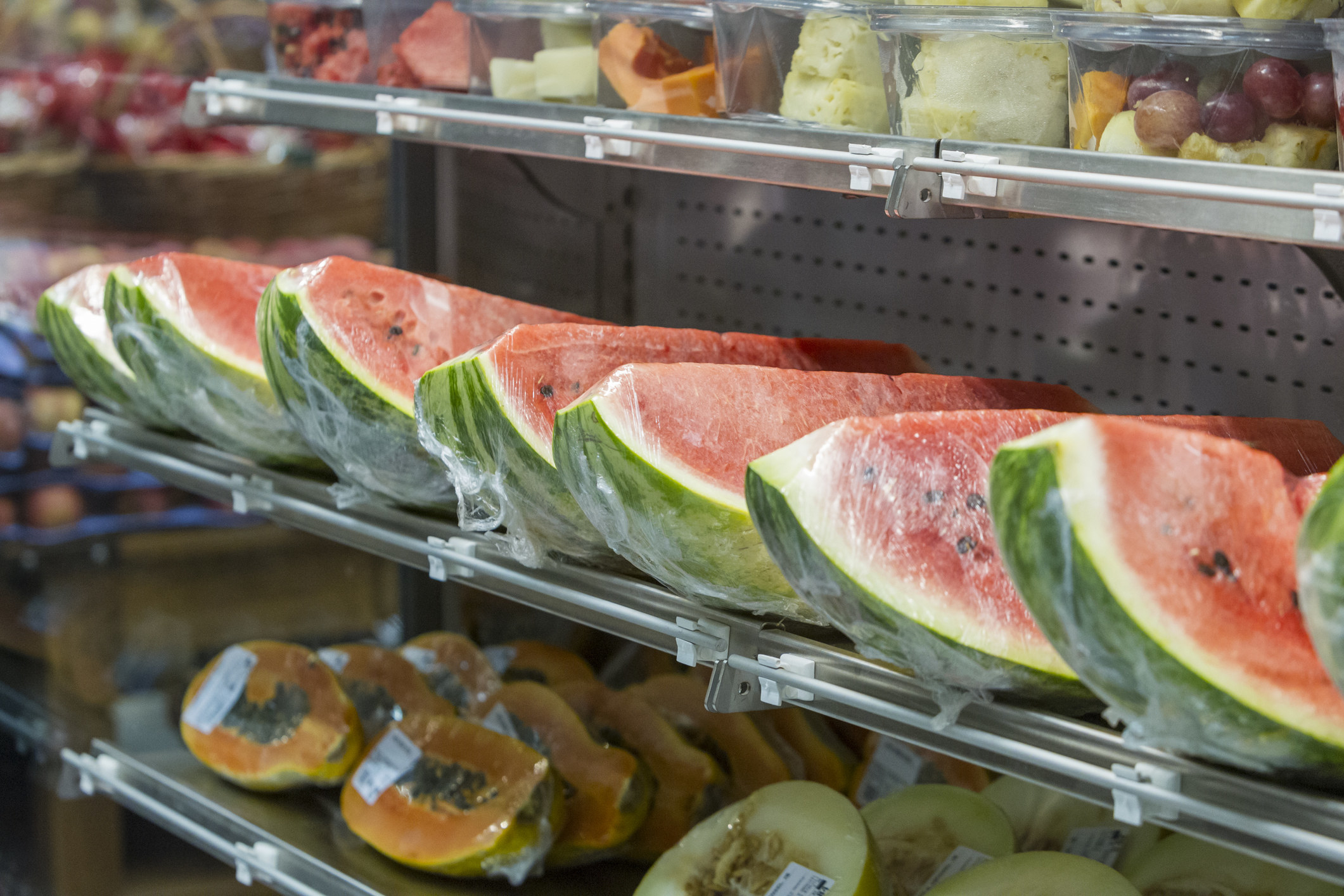 Displays of cut fresh fruit like watermelon wrapped in plastic