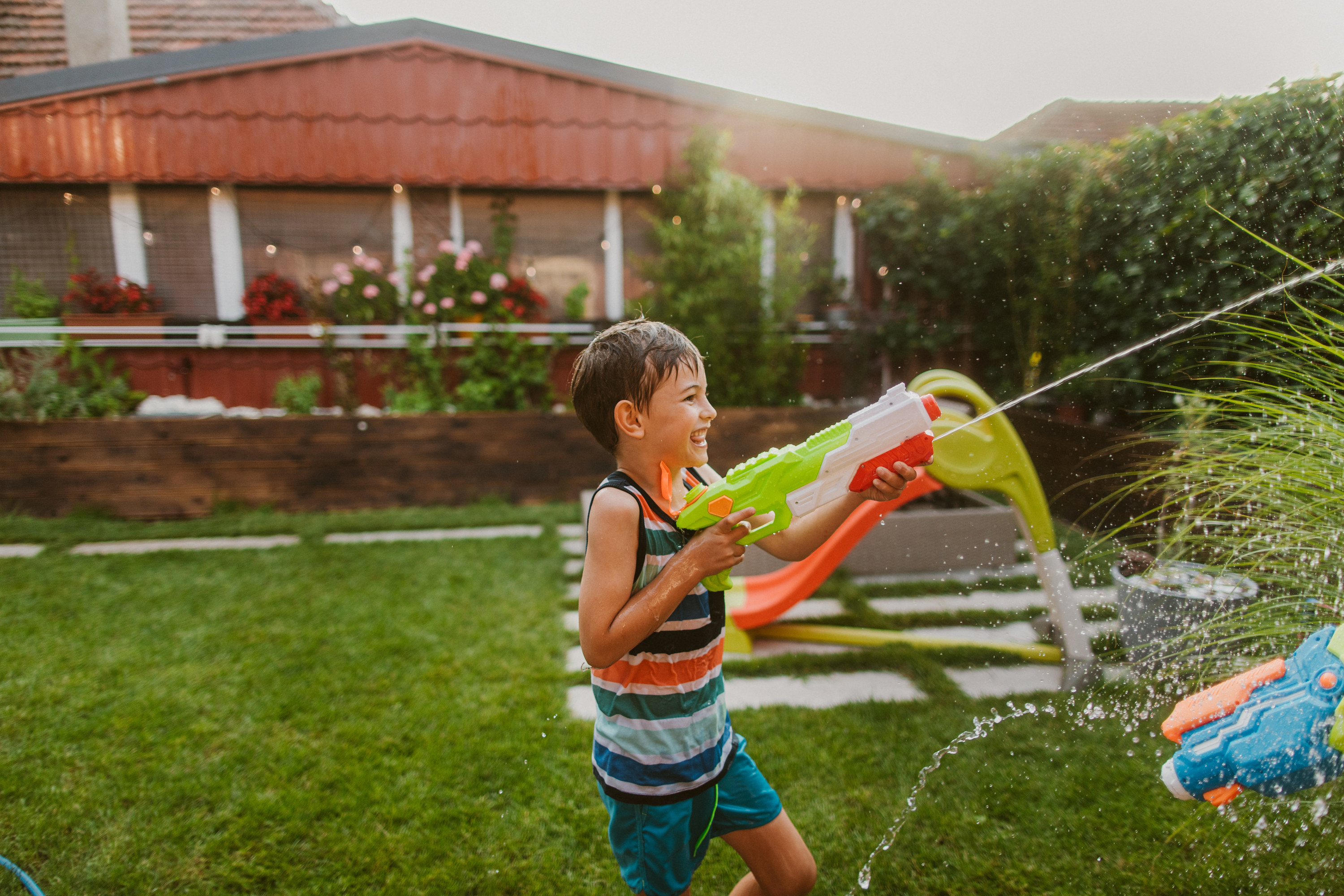 little boy using a water gun during a water fight in backyard