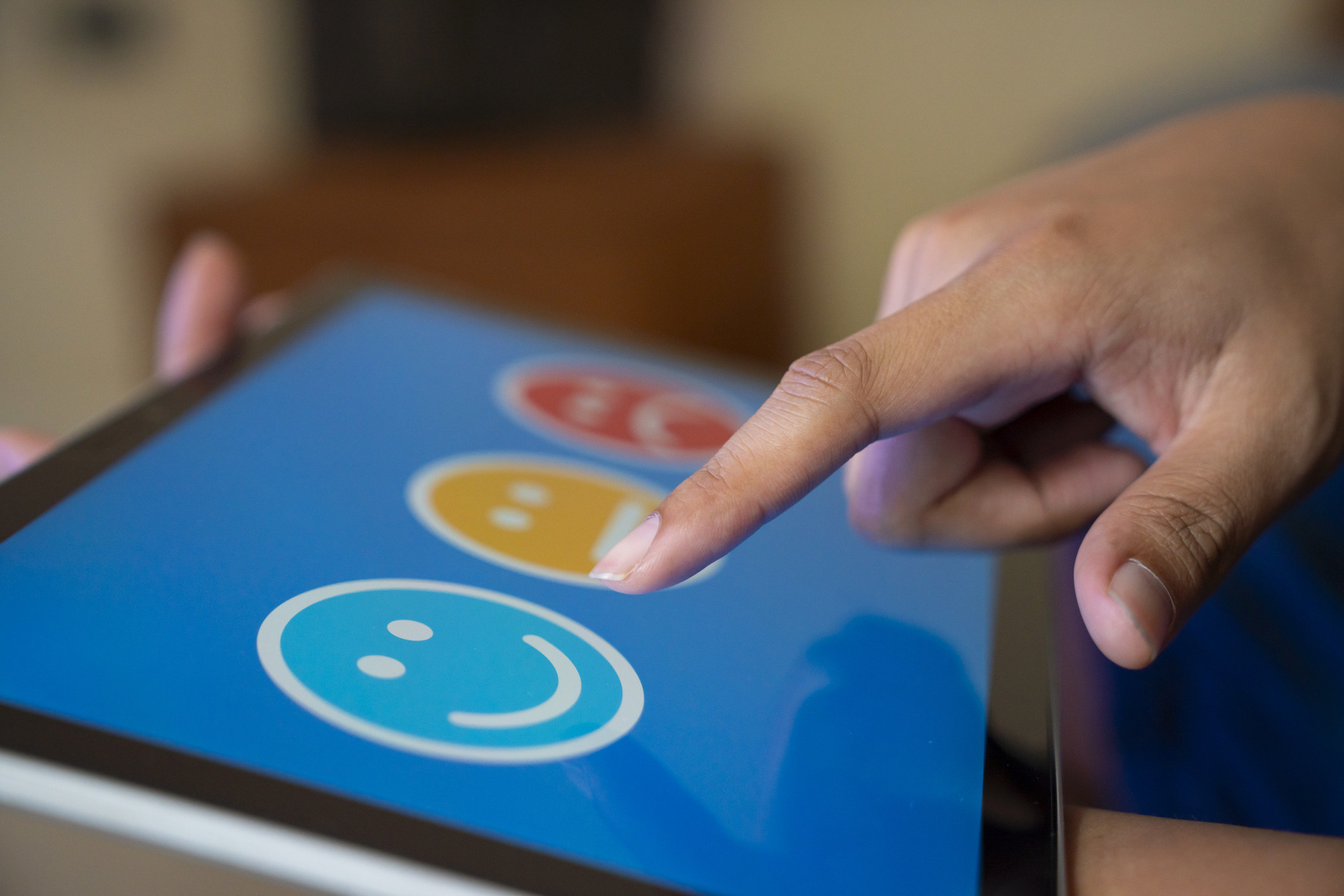 Person selecting a happy face on a tablet