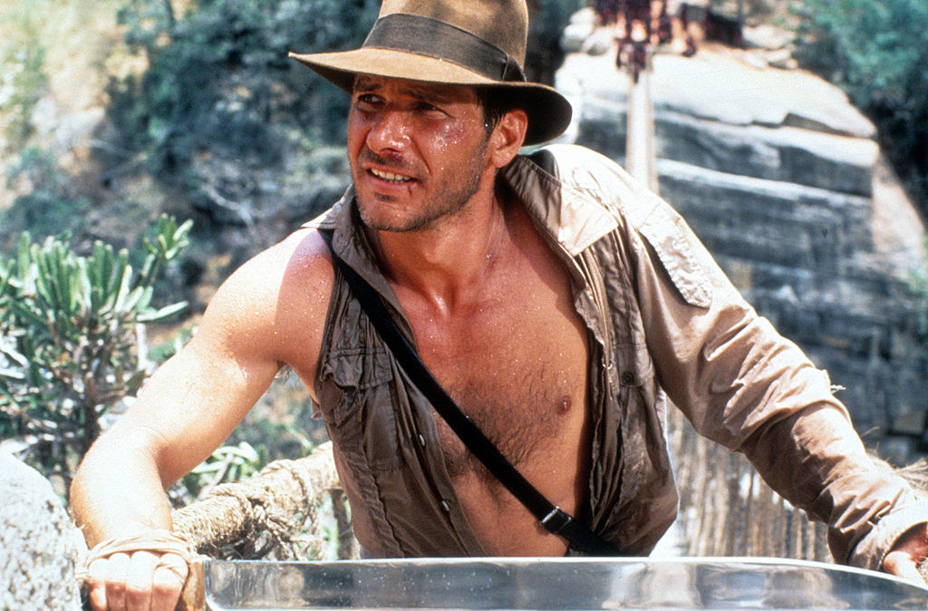 Harrison Ford as Indiana Jones with his shirt open and sleeve ripped