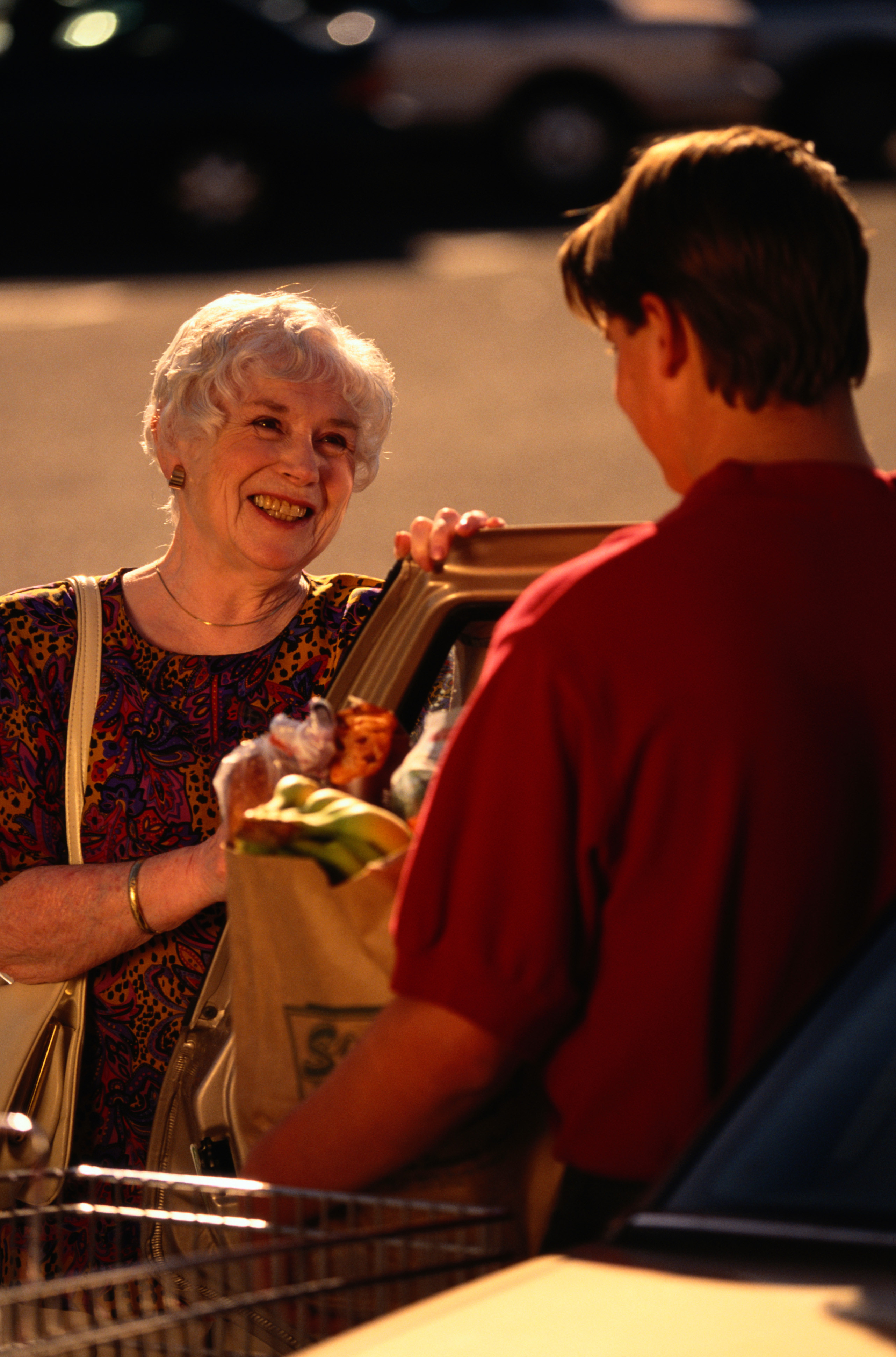 Woman smiling at a young person holding a bag of groceries