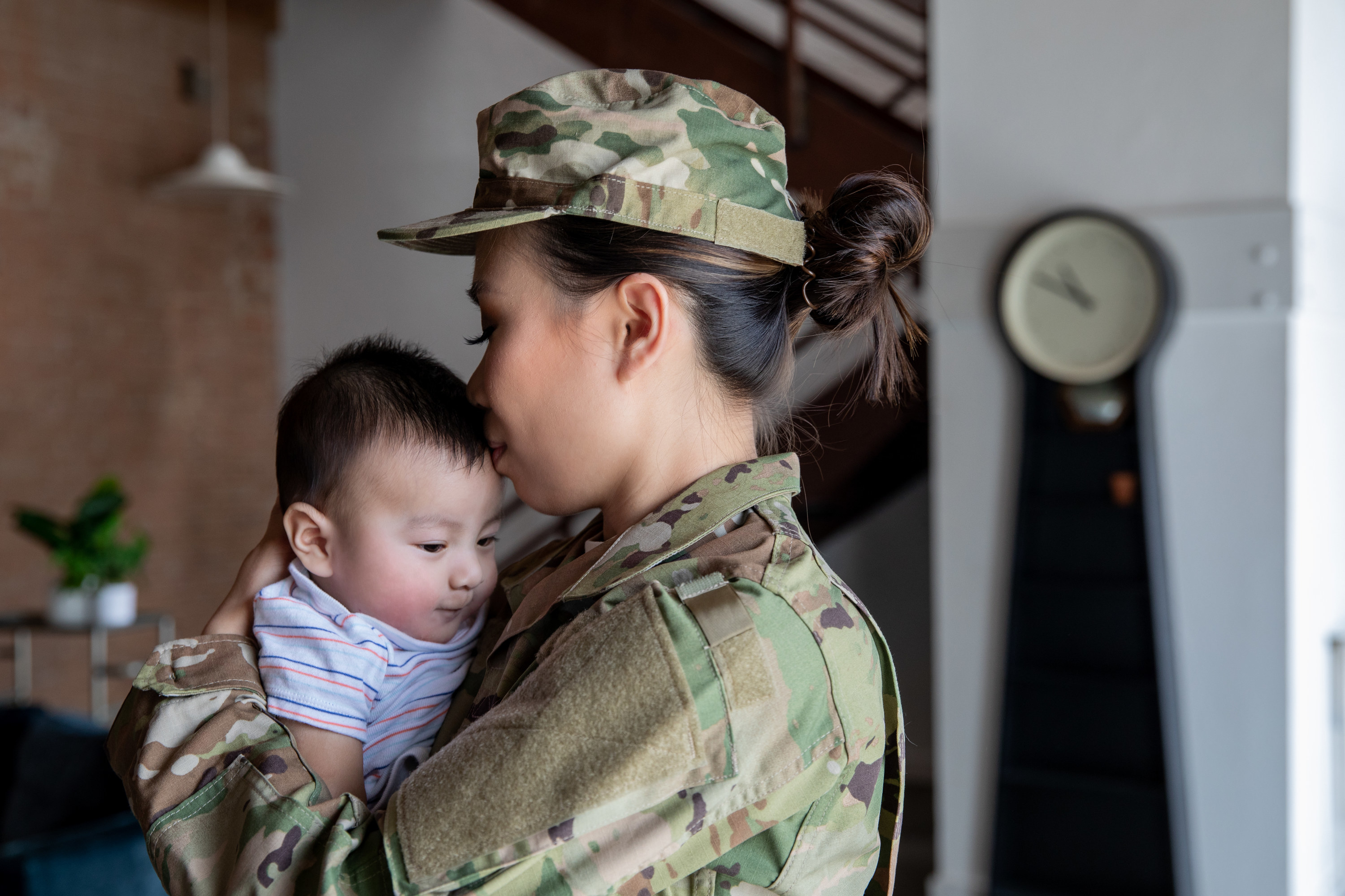 A military servicewoman kissing her baby on the forehead