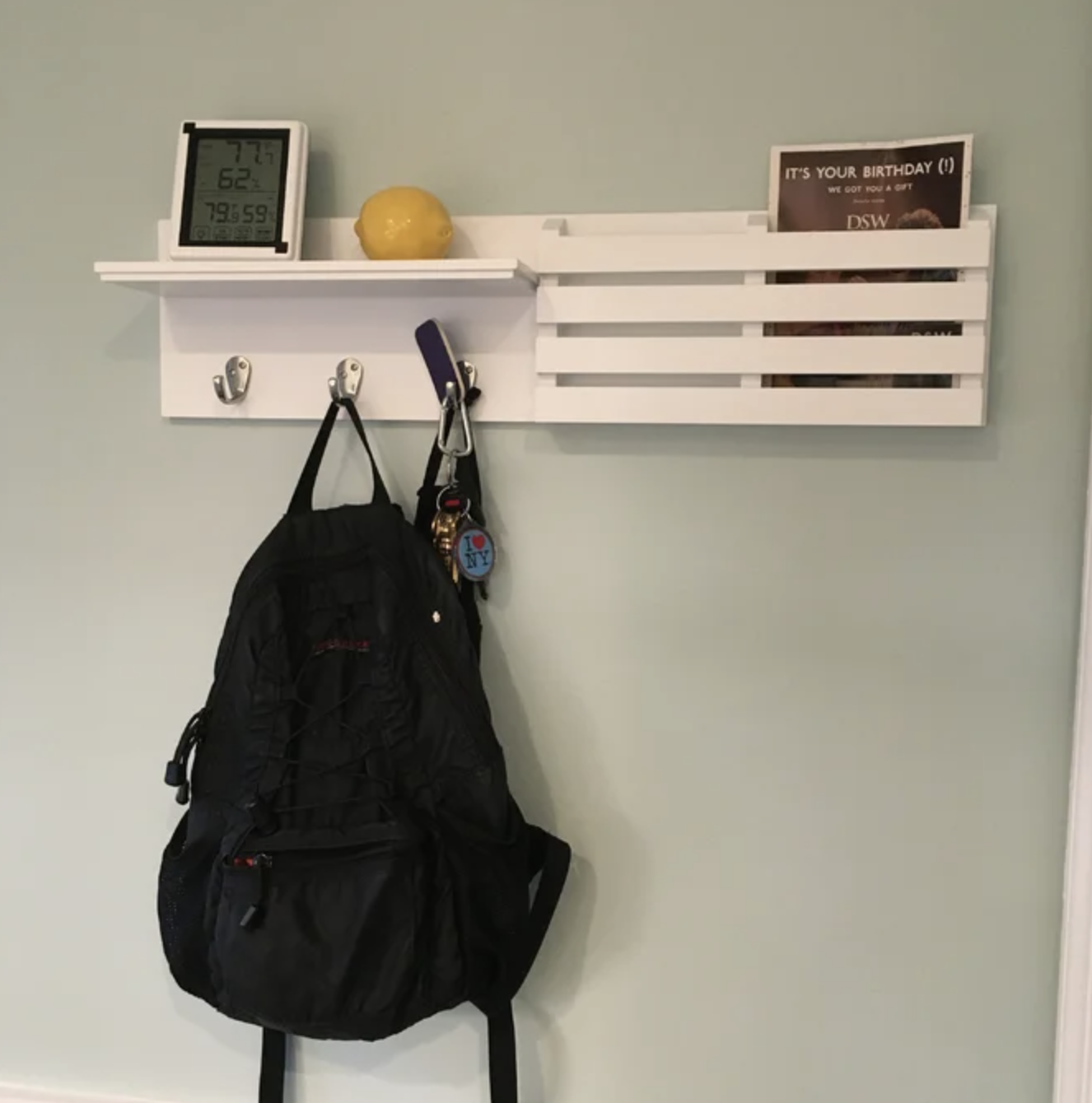 the white organizer with a backpack, keys, and a magazine on it