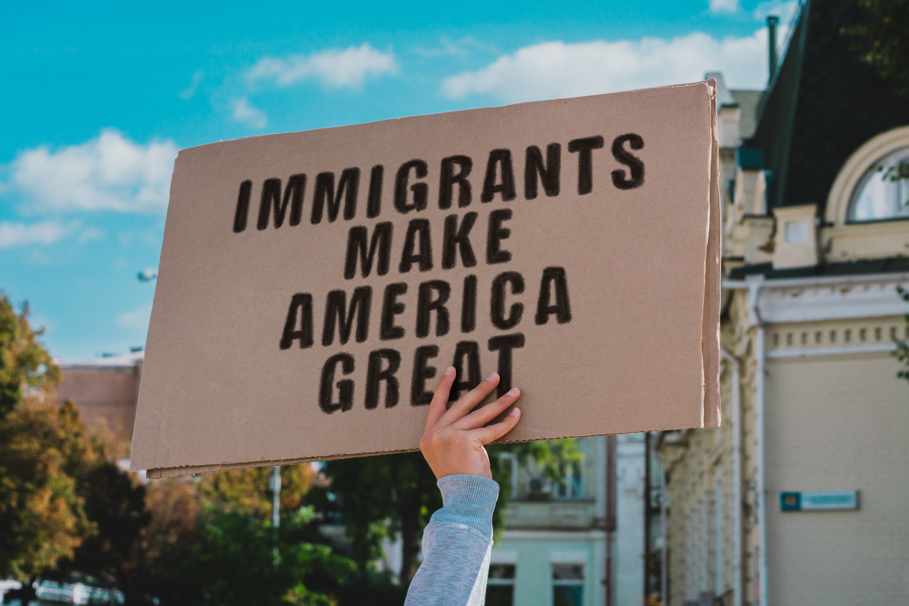 person holding a sign that says immigrants make america great