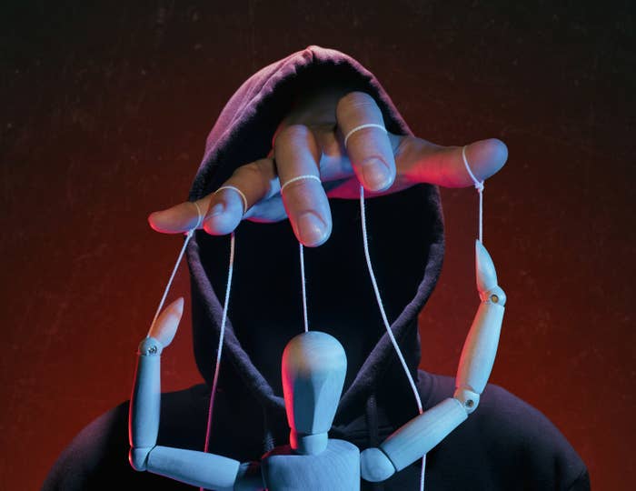 hand controlling a puppet symbolizing manipulation