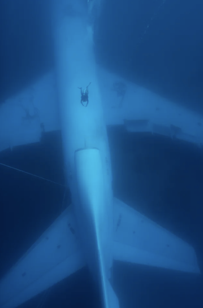 Scuba divers swim to a submerged plane