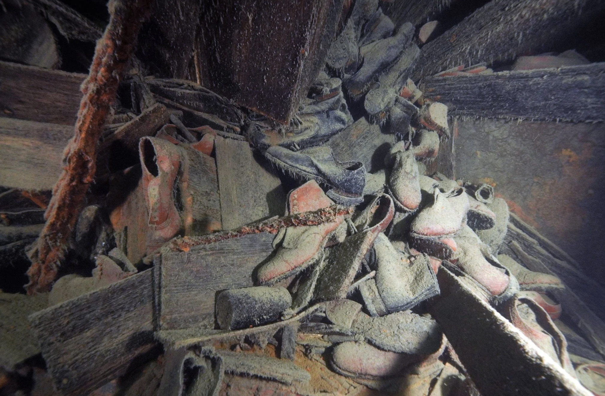 A pile of various water-worn clothes, including many shoes that look discolored