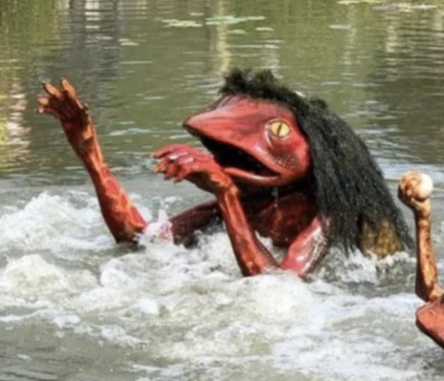 A partially submerged statue of an animal that makes it look like it&#x27;s a monster crawling out of the water