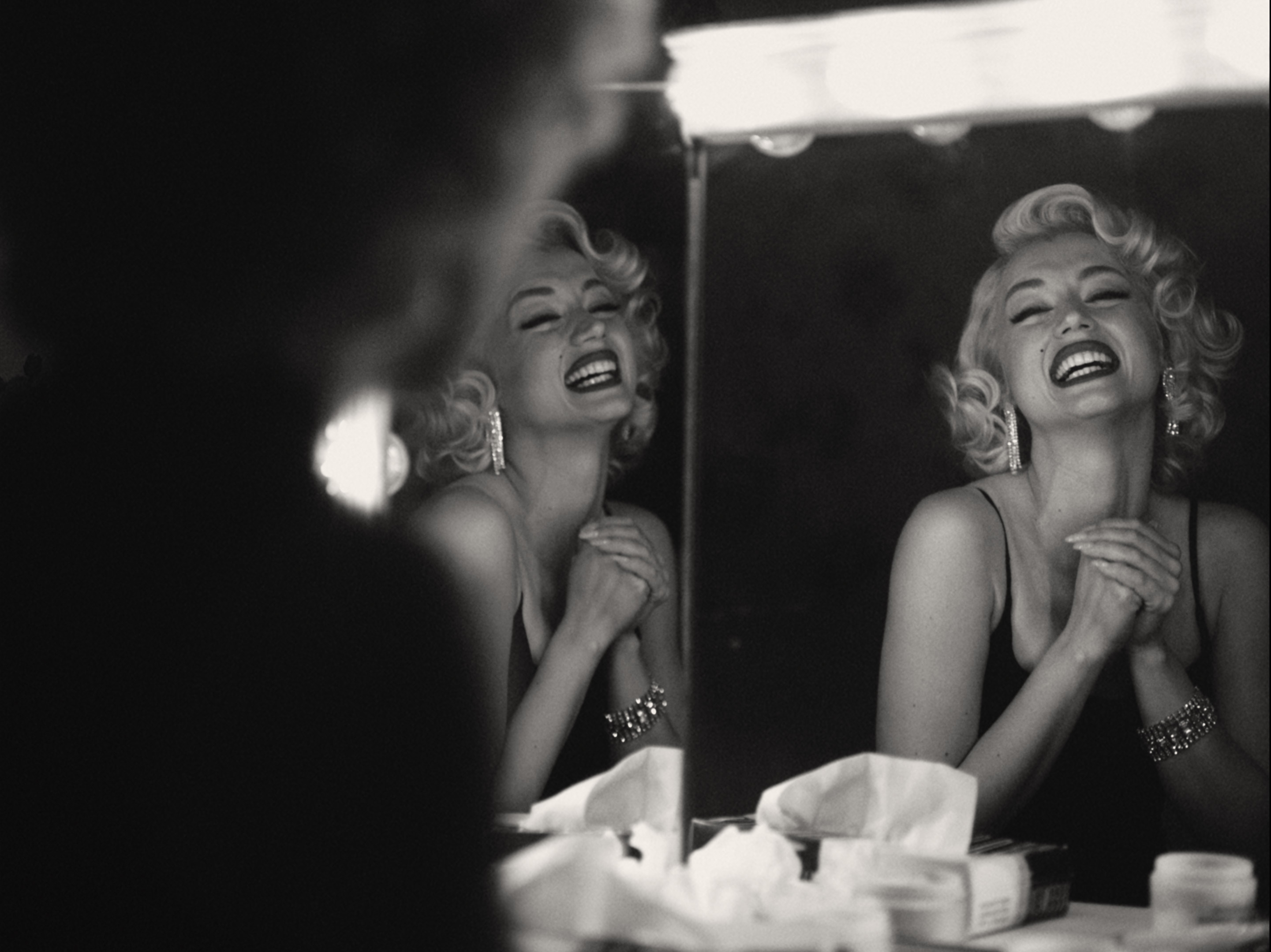 A woman smiling in the mirror and her reflection