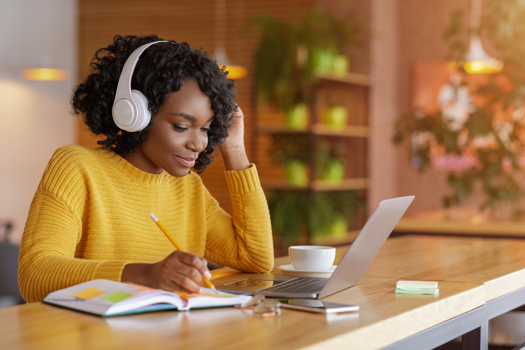 A woman works and listens on headphones