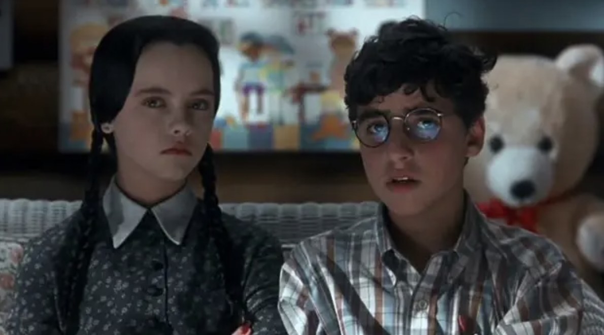 girl with black hair and boy with glasses sitting next to each other